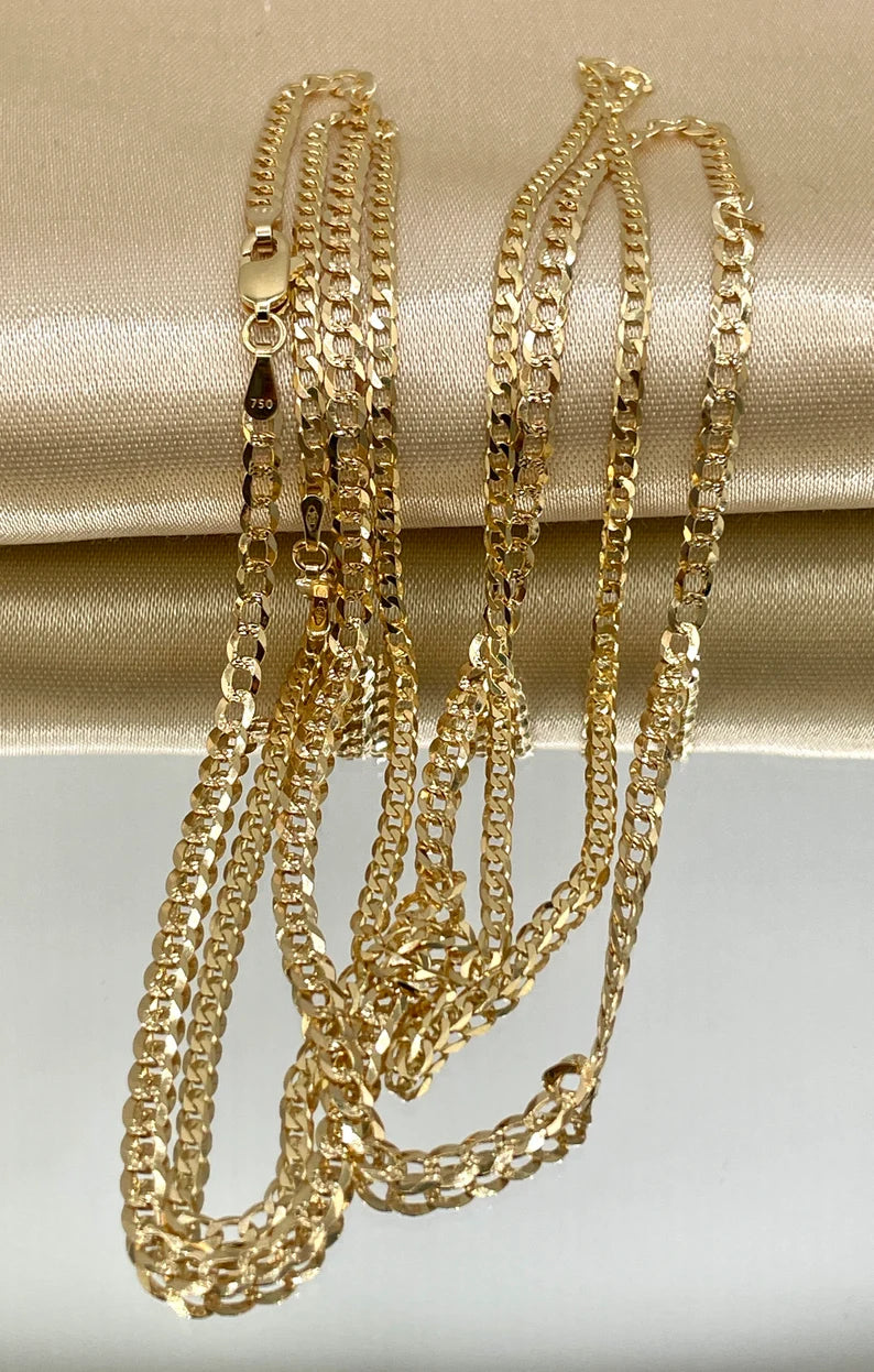 Three gold chains on a beige fabric background
