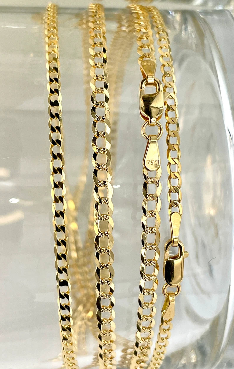 Three gold chains on a clear glass surface
