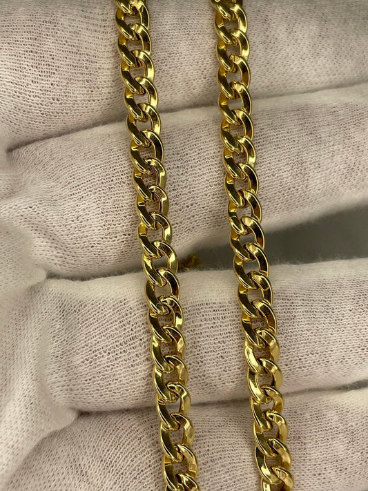 Two gold chains on a textured beige surface