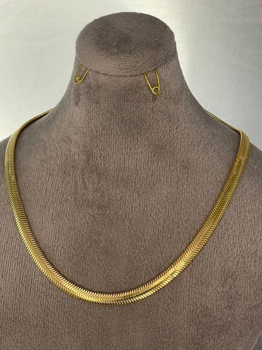 Gold necklace on a mannequin with a plain background