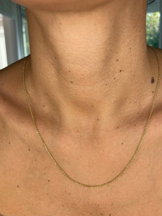 Gold necklace on a person's neck with a blurred background
