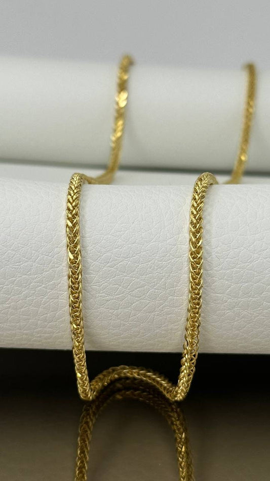 Gold chain necklace on a white cushion