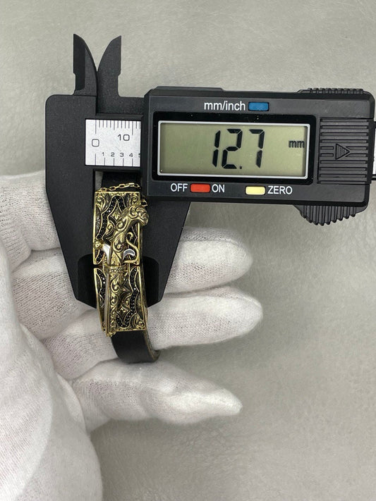 Gold bracelet being measured with a digital caliper on a gray background