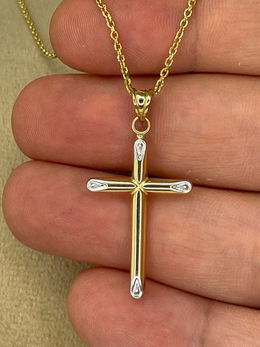 Gold cross pendant on a chain held between fingers