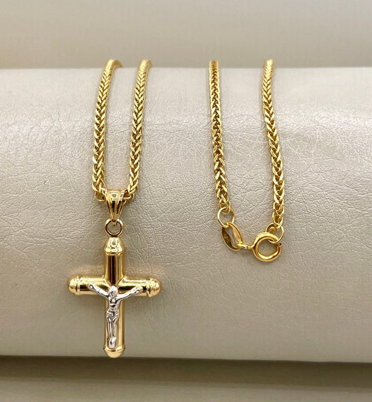 Gold necklace with a cross pendant on a beige surface