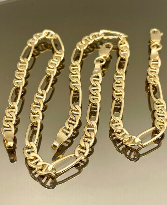 Gold chain necklace and bracelet set on a reflective surface