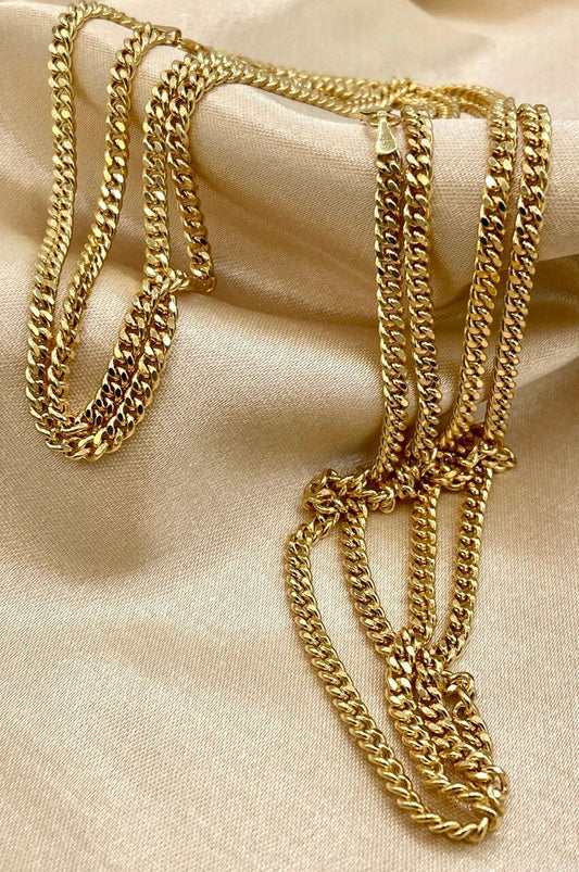 Gold chain necklaces on a beige fabric background