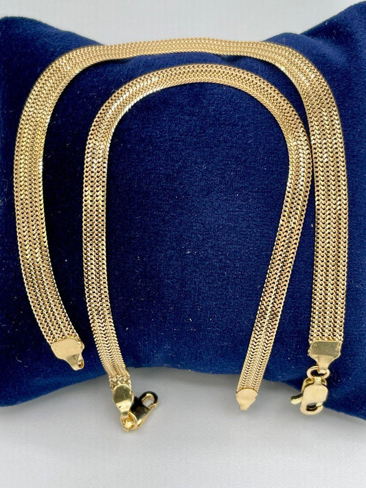 Two gold necklaces on a blue cushion