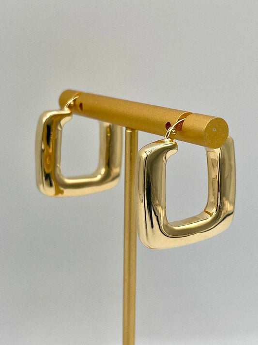 Gold hoop earrings on a gray background