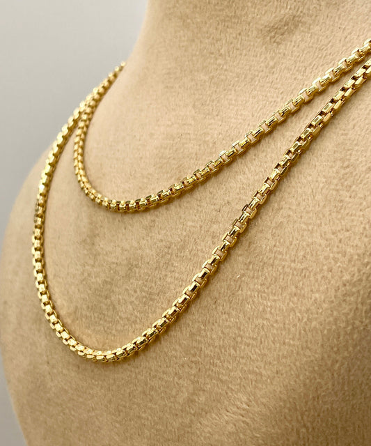 Gold chain necklace on a mannequin bust against a neutral background