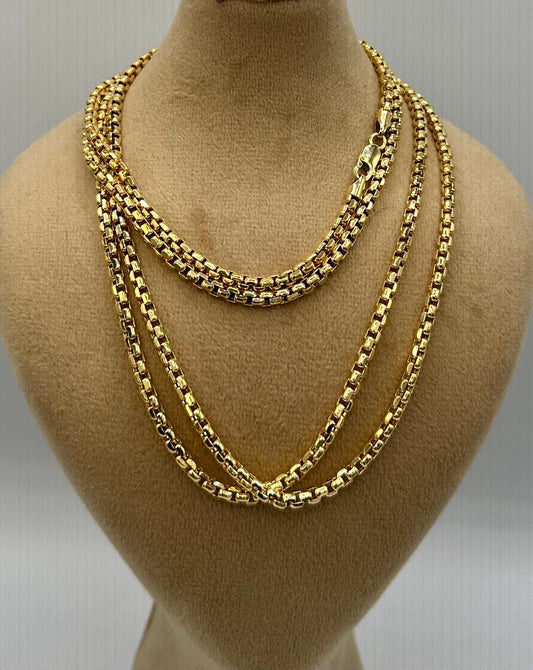 Three gold chains displayed on a mannequin bust against a neutral background