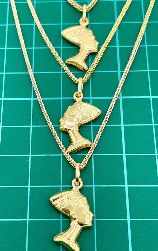 Three gold necklaces with pendant heads on a green grid background
