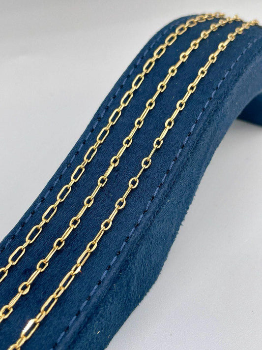 Gold chain on a blue leather strap against a gray background