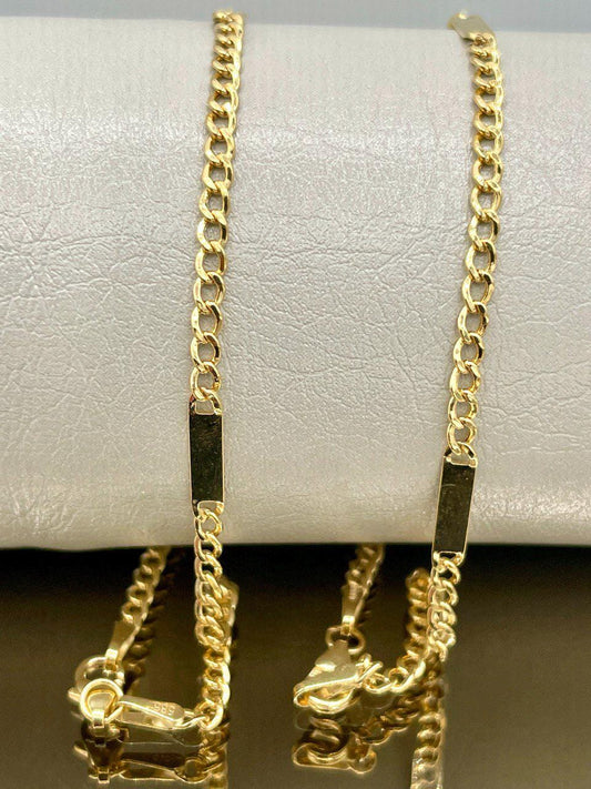 Two gold chains on a white cushion with a brown background