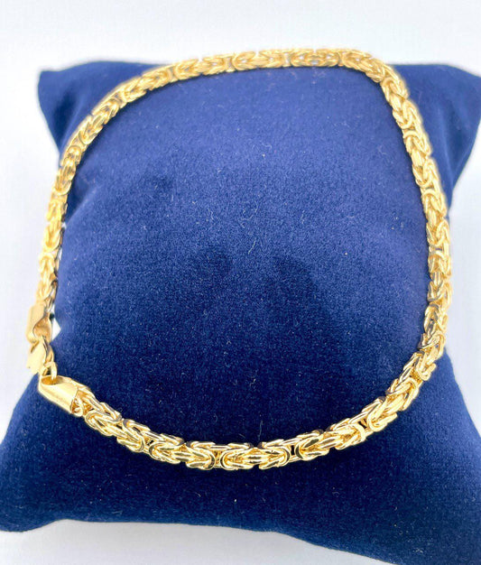 Gold chain necklace on a blue cushion