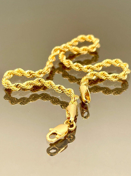 Gold rope chain necklace on a reflective surface