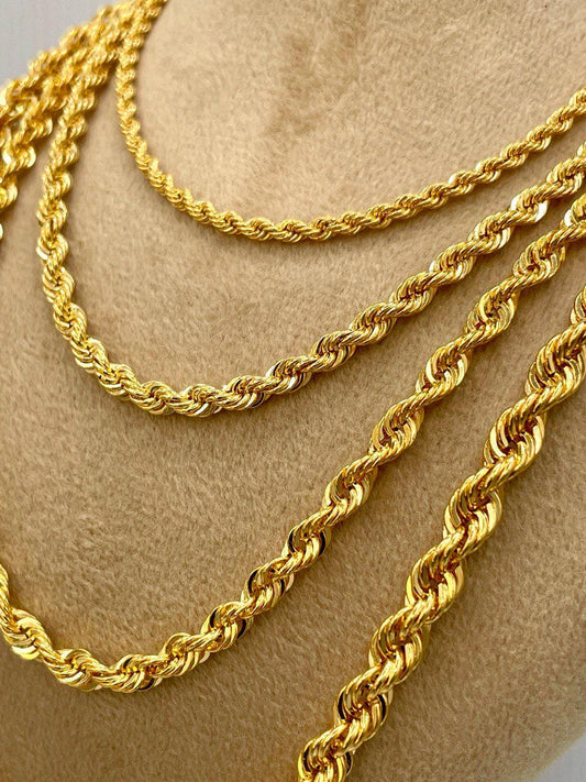 Three gold rope chains on a beige surface