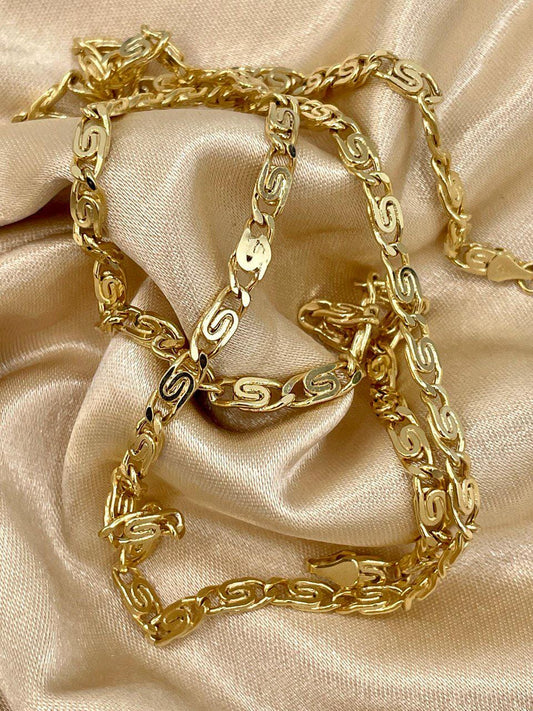 Two gold chain necklaces on a beige satin background