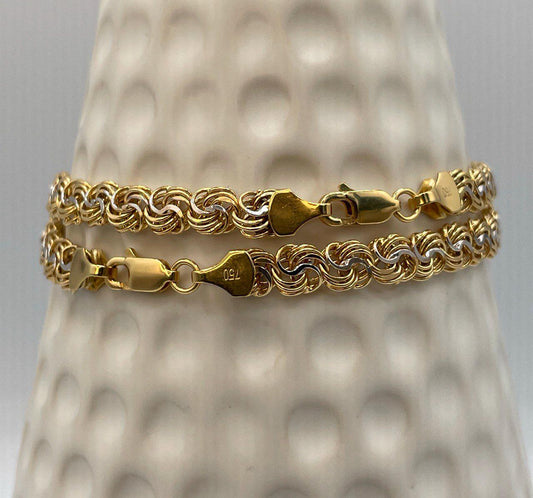 Gold chain bracelet on a textured gray stand