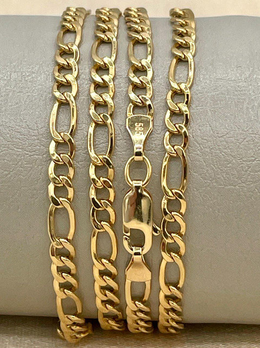 Three gold chain bracelets on a gray surface