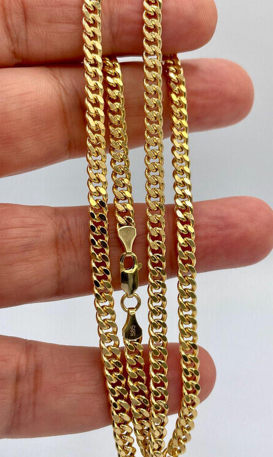 Gold chain held between fingers with a plain background