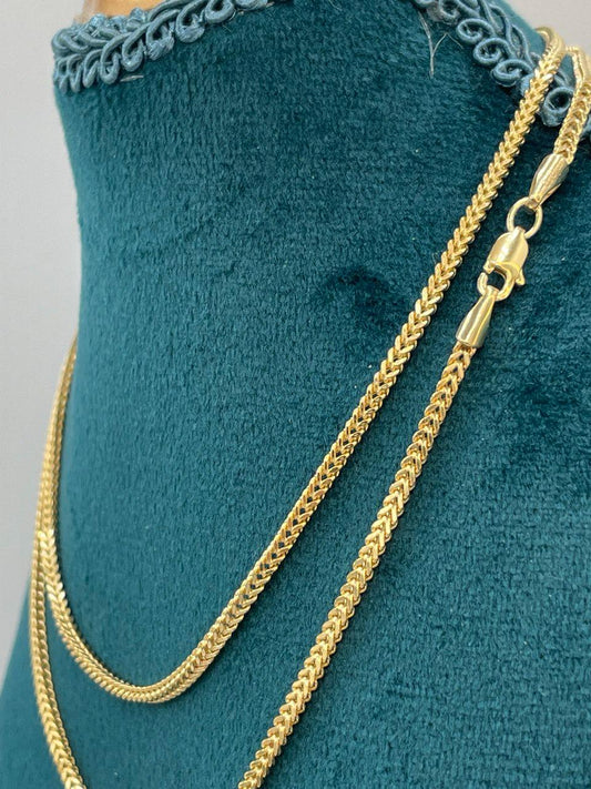 Gold chain necklace on a green velvet cushion