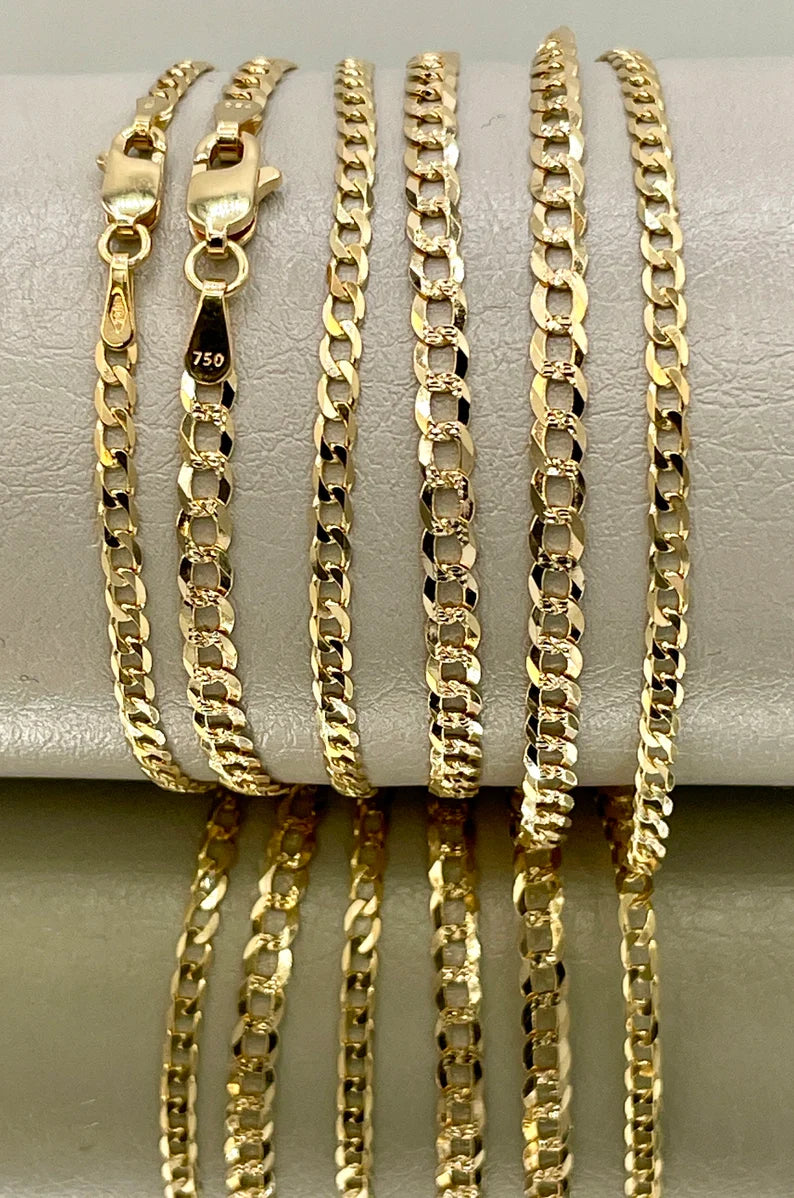 Gold chains of different designs and thicknesses on a white surface