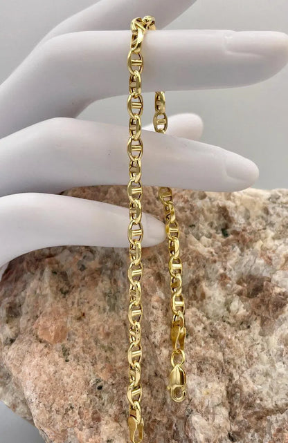 Gold chain held by a hand against a stone background