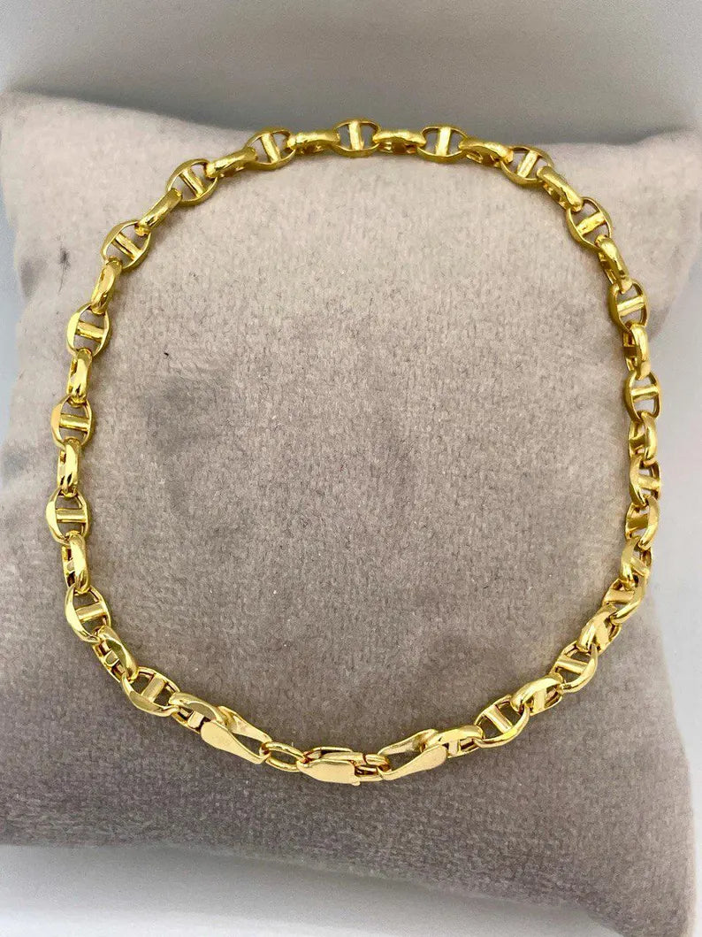 Gold chain necklace on a gray cushion