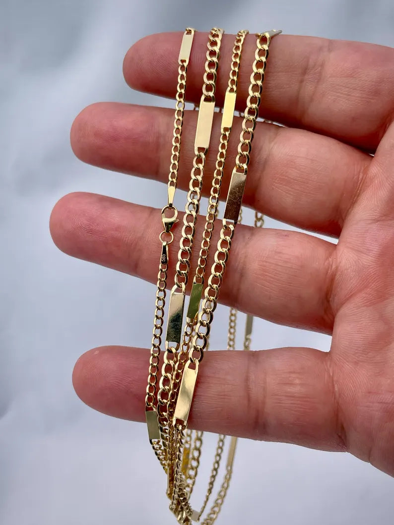 Gold chains displayed on a hand against a neutral background