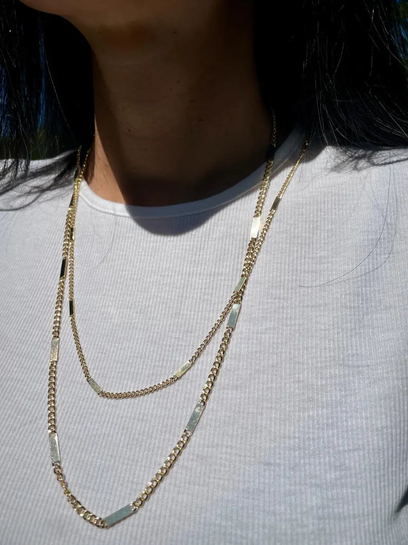 Person wearing a gold necklace with a white shirt
