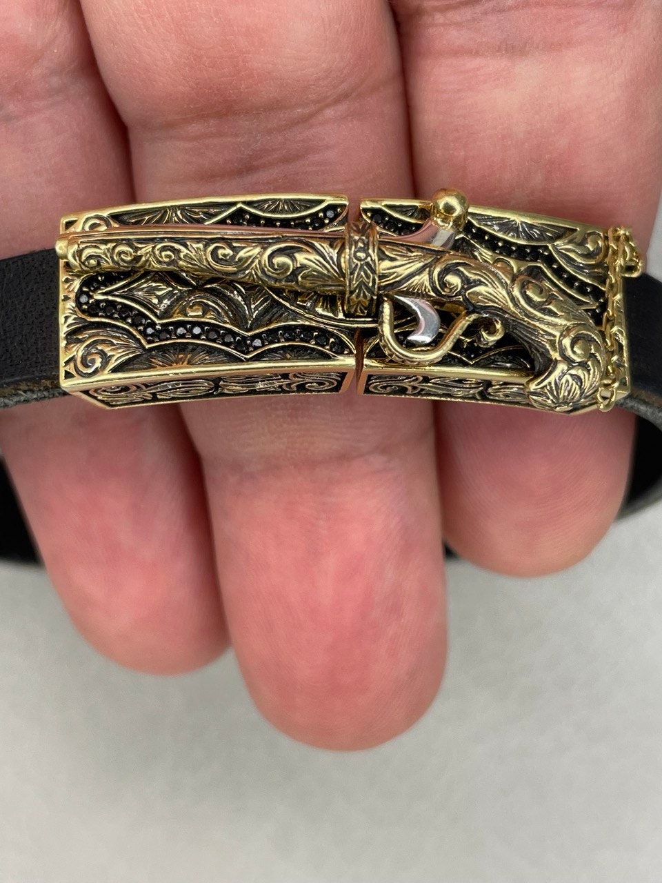 Gold decorative object held between fingers on a light background