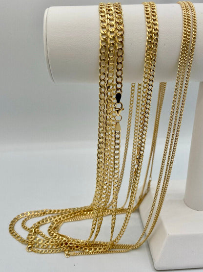 Gold chains displayed on a white cylindrical stand against a light gray background