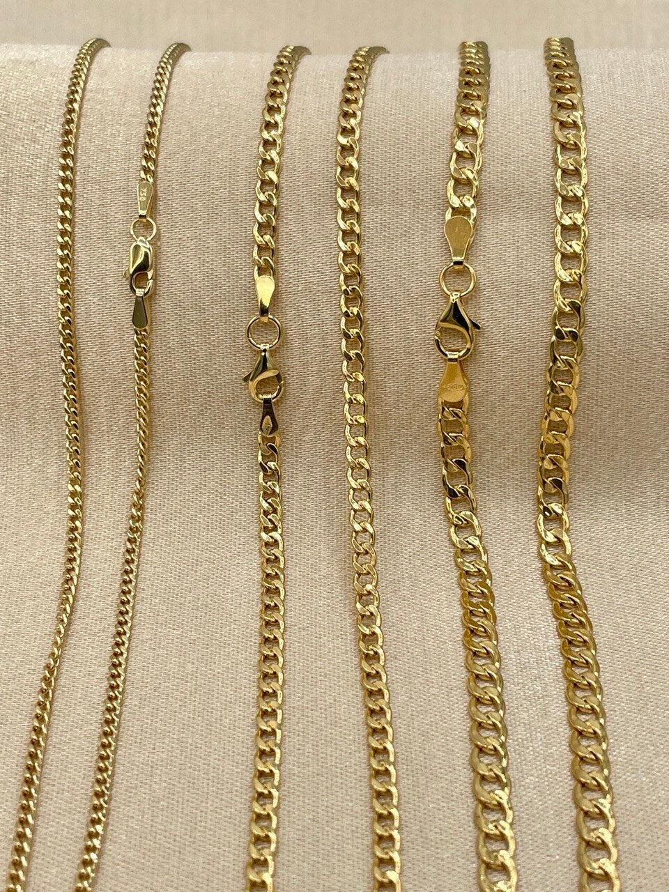 Set of gold chain necklaces on a beige fabric background