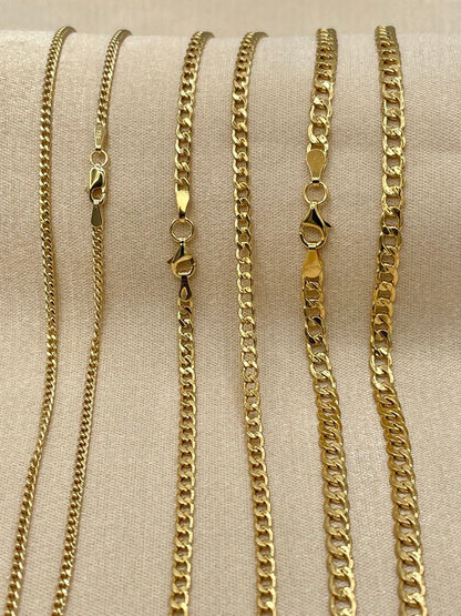 Set of gold chain necklaces on a beige fabric background