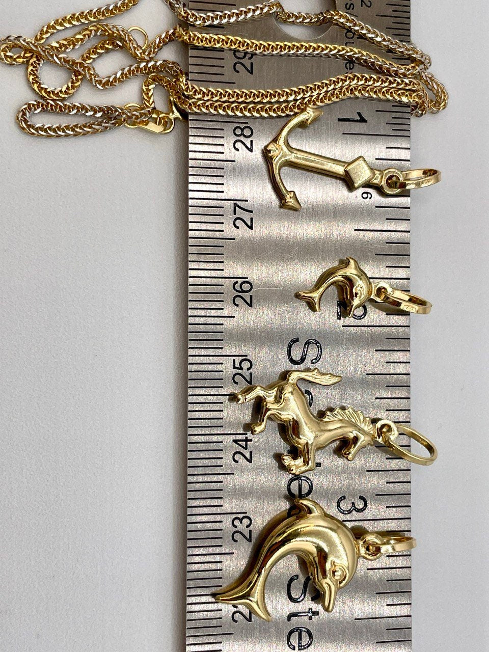 Gold pendants on a ruler for size reference