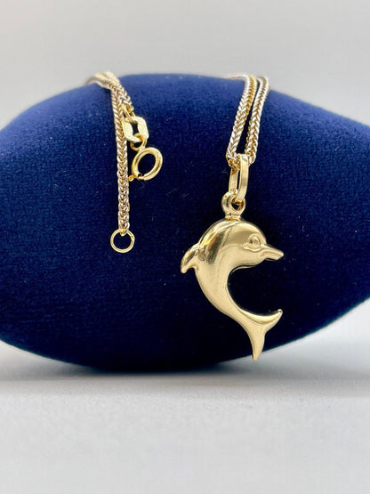 Gold dolphin pendant necklace on a blue jewelry display