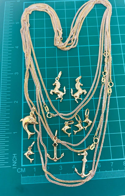 Gold necklace with various pendants on a teal cutting mat with measurements.