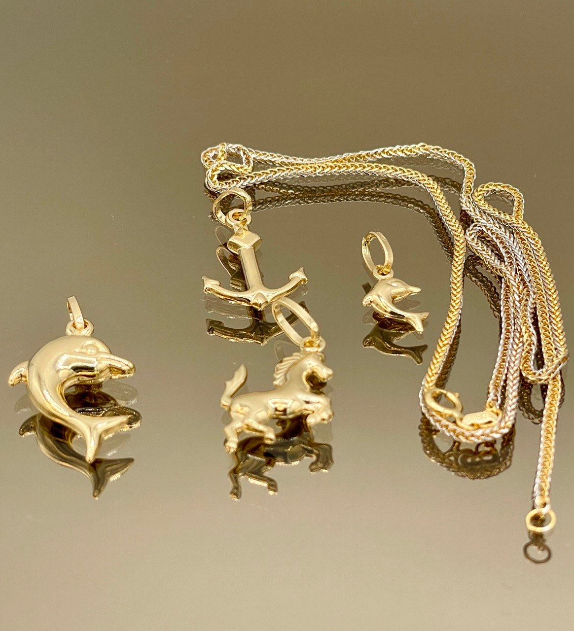 Gold animal pendants on a gold chain against a reflective surface