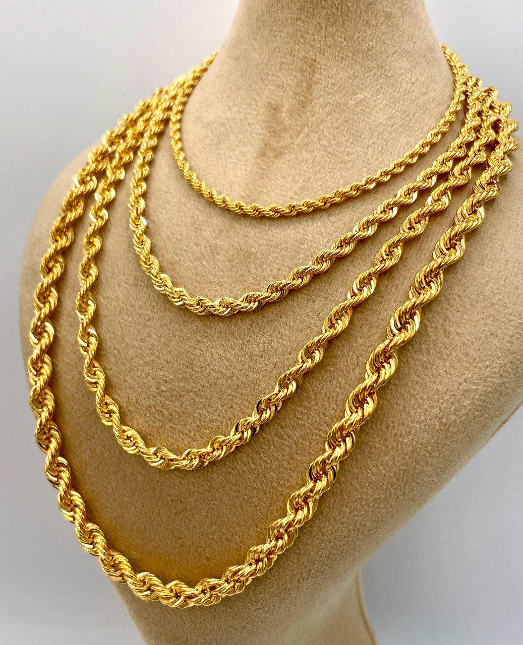 Three gold chains stacked on a mannequin neck against a white background