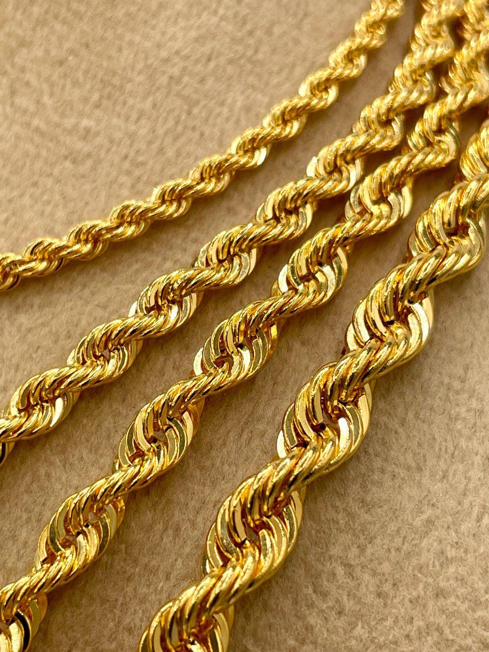 Three gold rope chains on a beige background