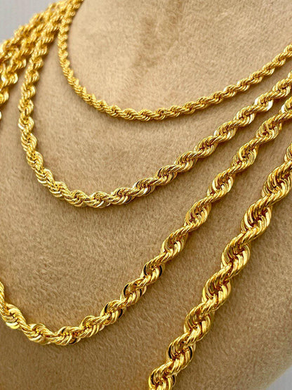 Three gold rope chains on a beige surface