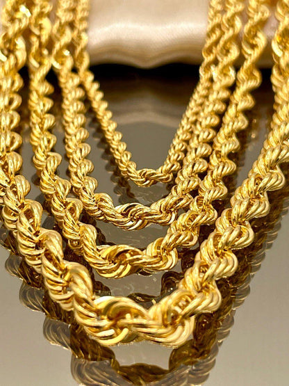 Close-up of three gold rope chains on a reflective surface