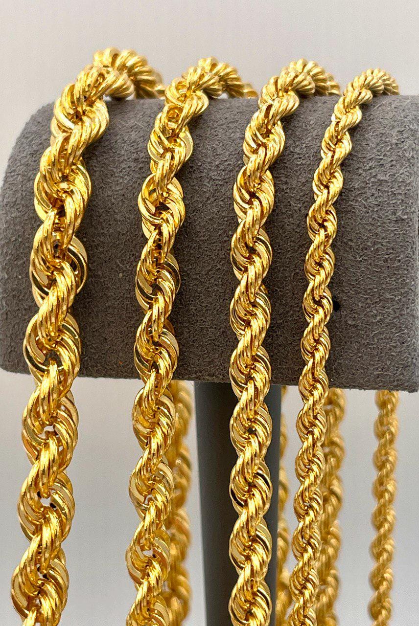 Three gold rope chains on a gray stand against a light gray background