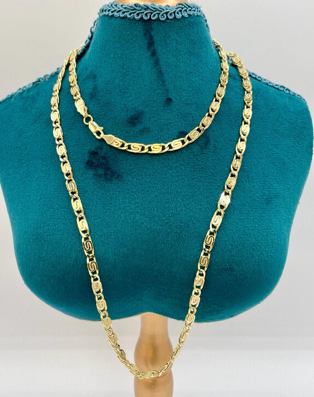 Gold chain necklace displayed on a teal mannequin bust.