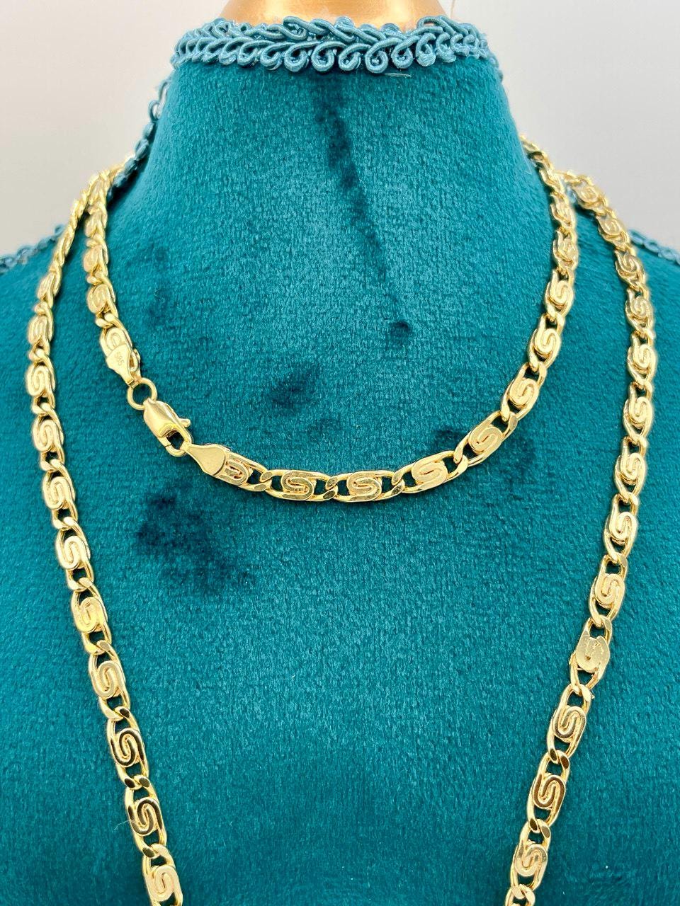 Gold chain necklace on a turquoise mannequin bust