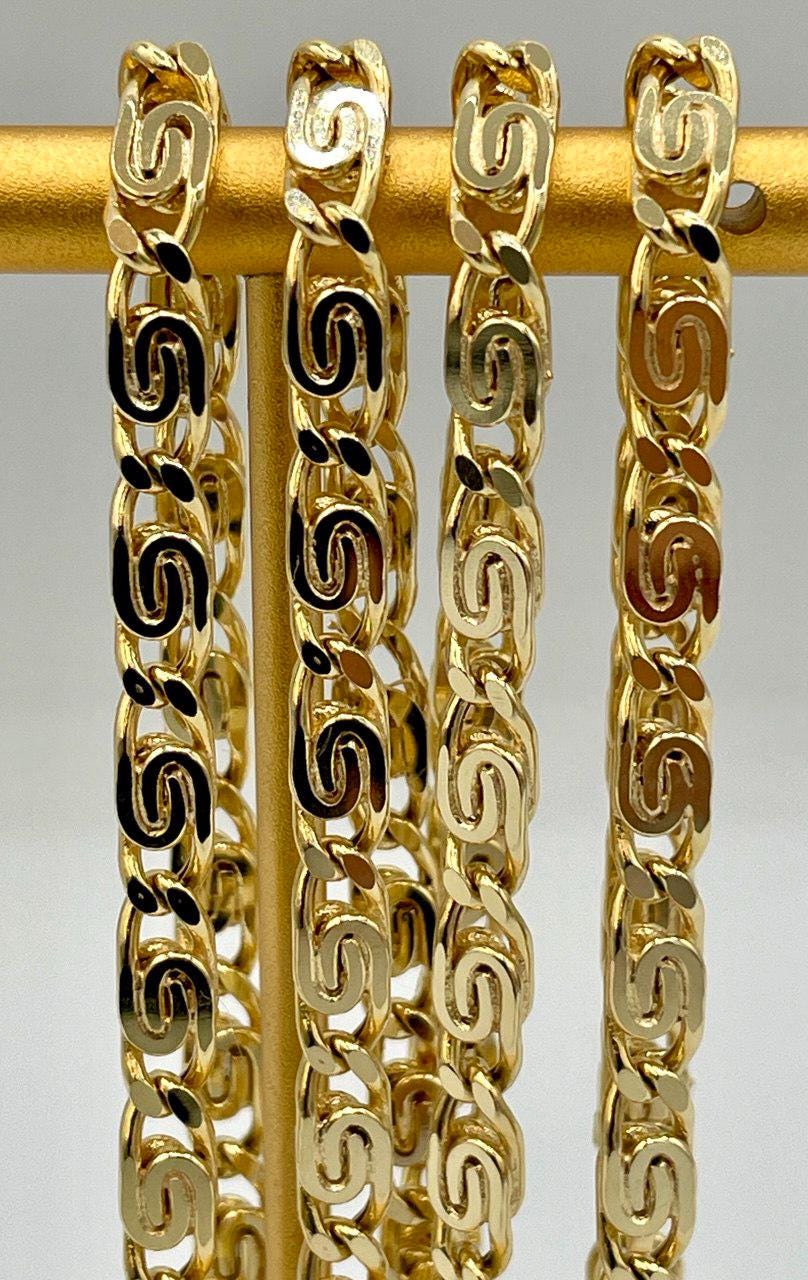 Gold chain bracelet on a gold stick against a gray background