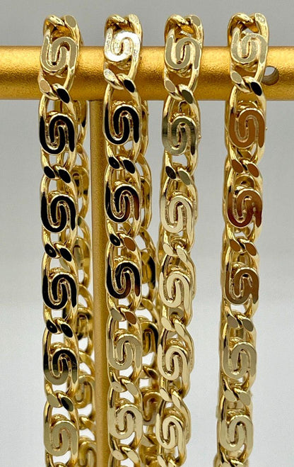 Gold chain bracelet on a gold stick against a gray background