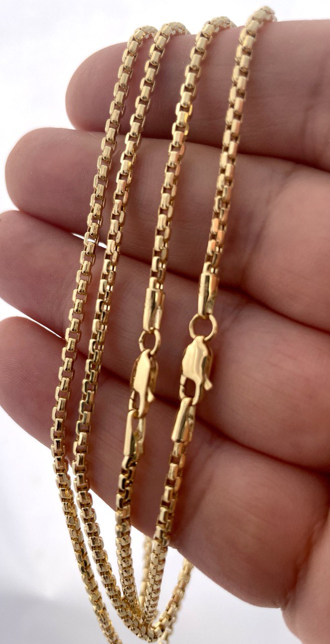 Gold chain held between fingers against a white background
