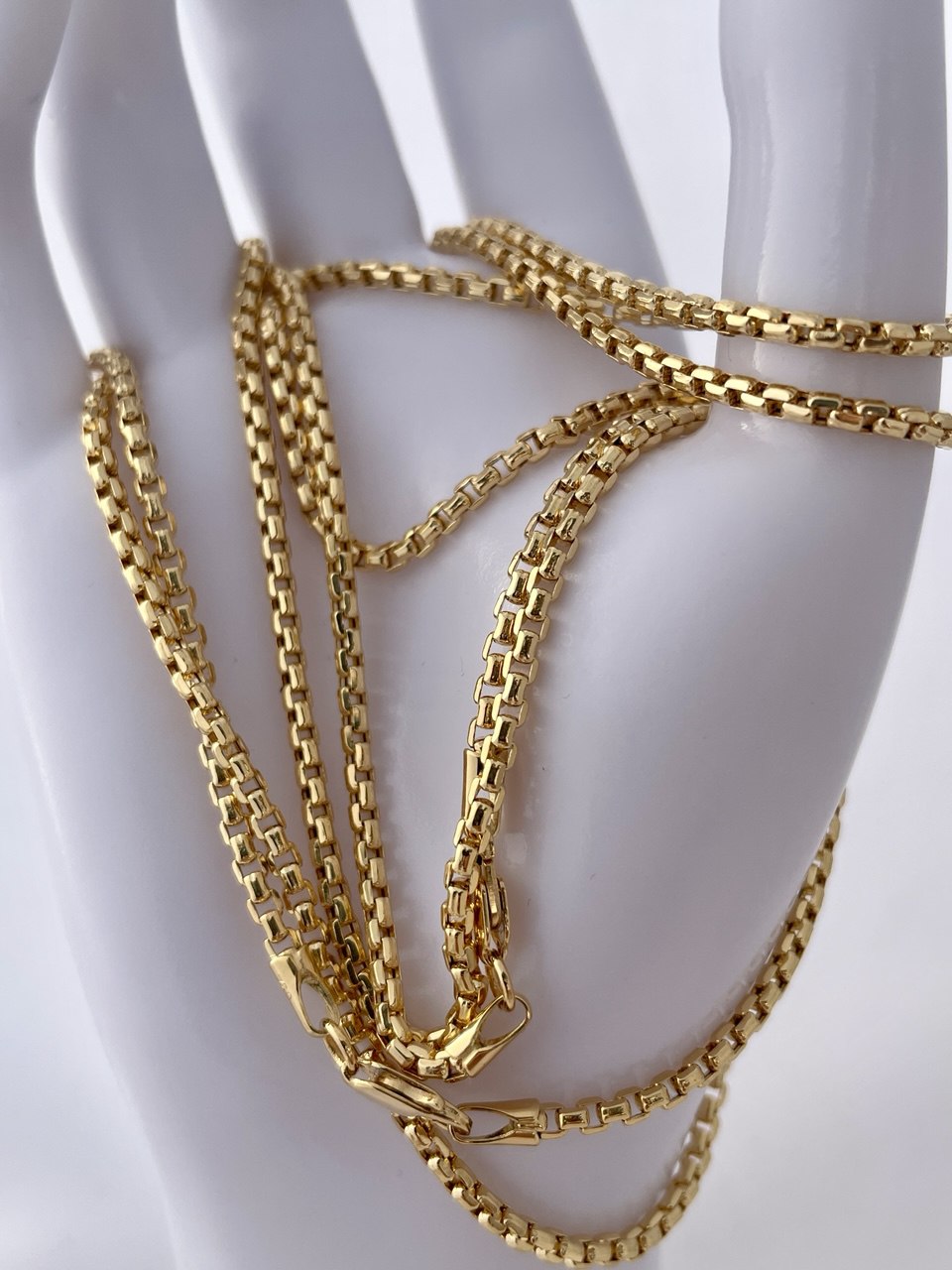 Gold chain necklace on a white mannequin